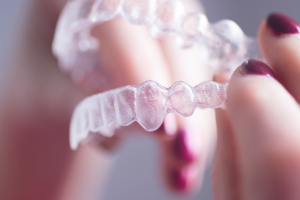 Patient holding a clear aligner tray at a Burleigh Waters dental clinic on the Gold Coast