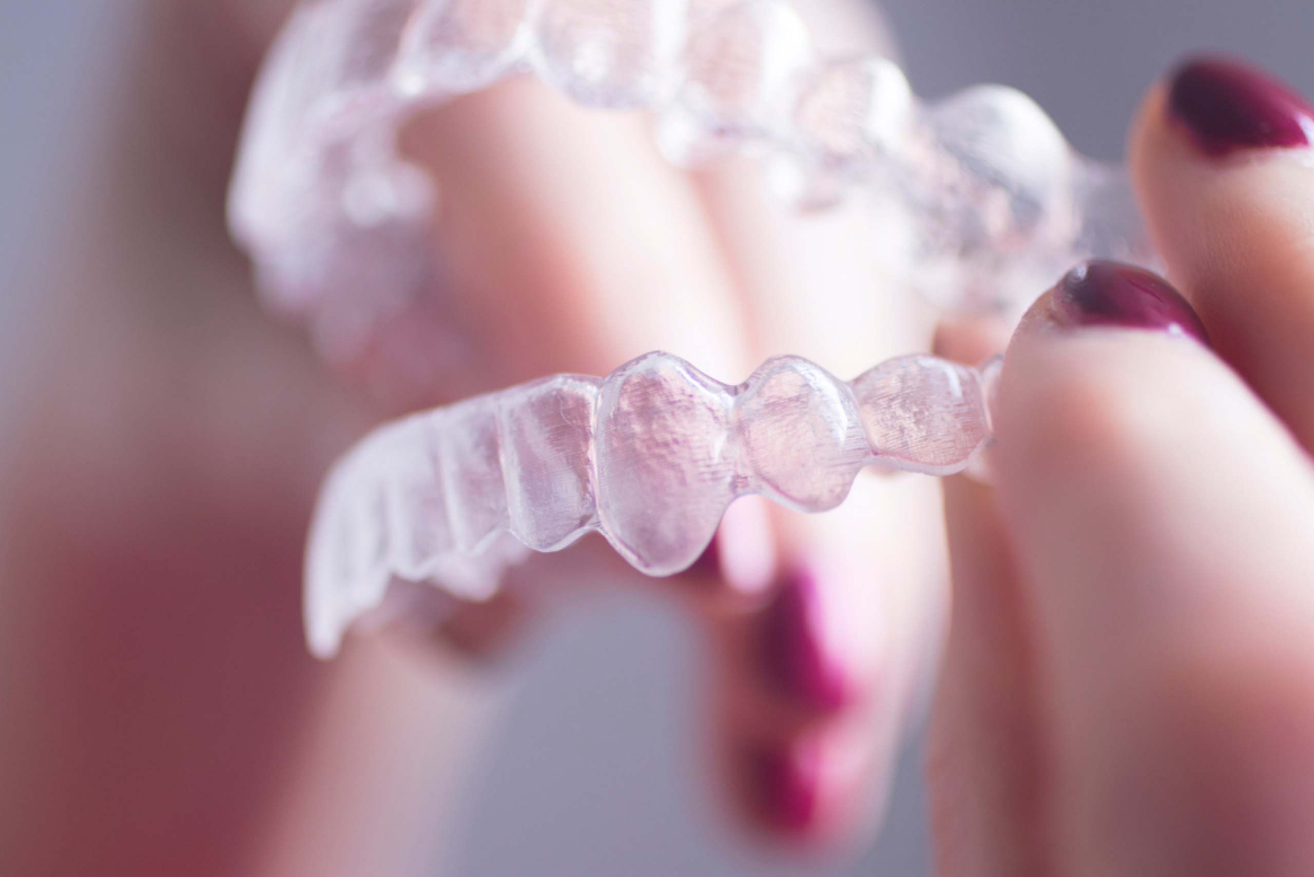 Patient holding a clear aligner tray at a Burleigh Waters dental clinic on the Gold Coast